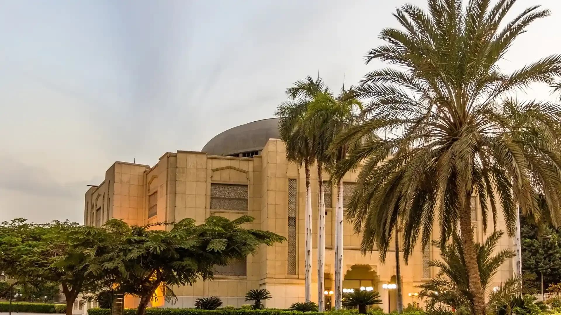 The Cairo Opera House at dusk among palm trees