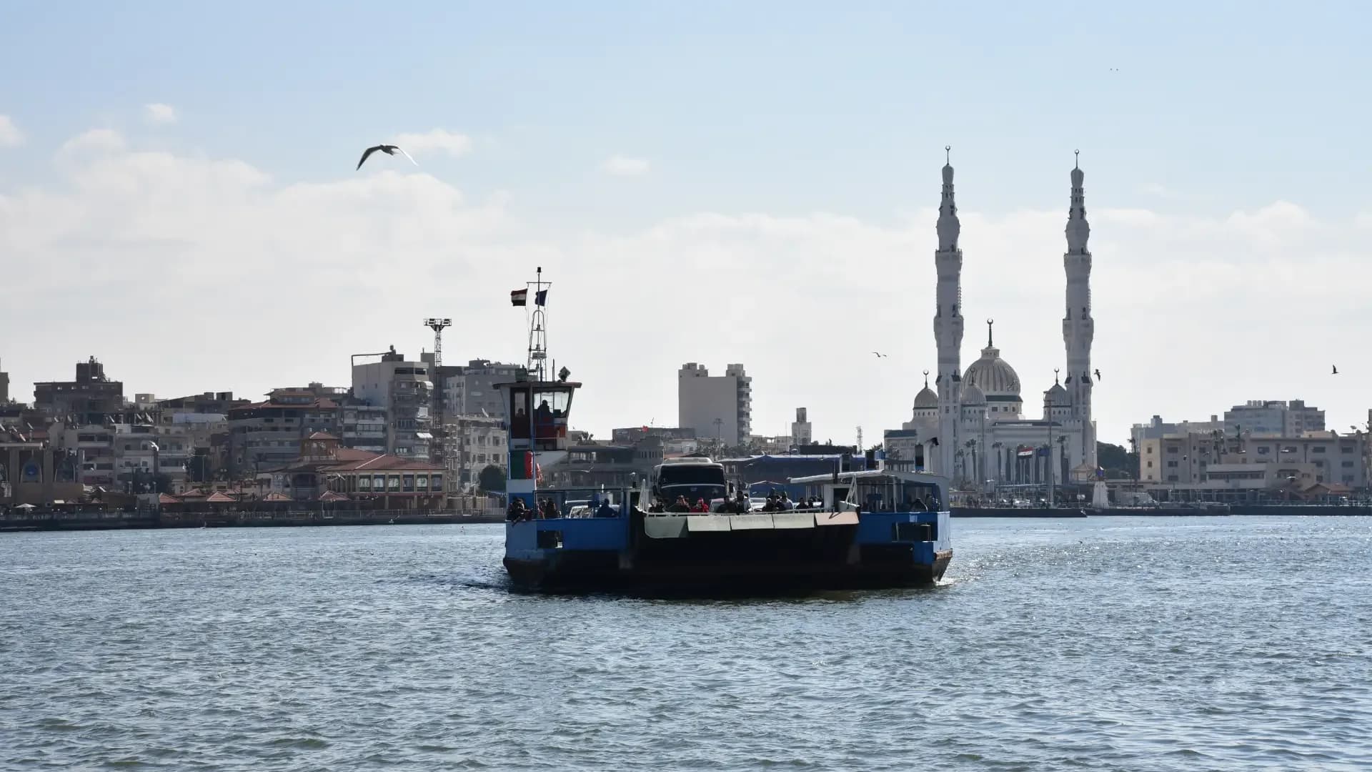 A ferry crossing the Suez Canal at Port Said, with the twin minarets of a mosque on the waterfront
