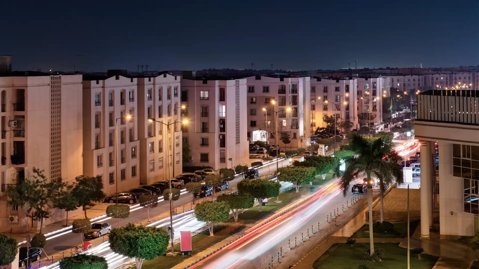 Apartment buildings and light trails on a boulevard in New Cairo at night