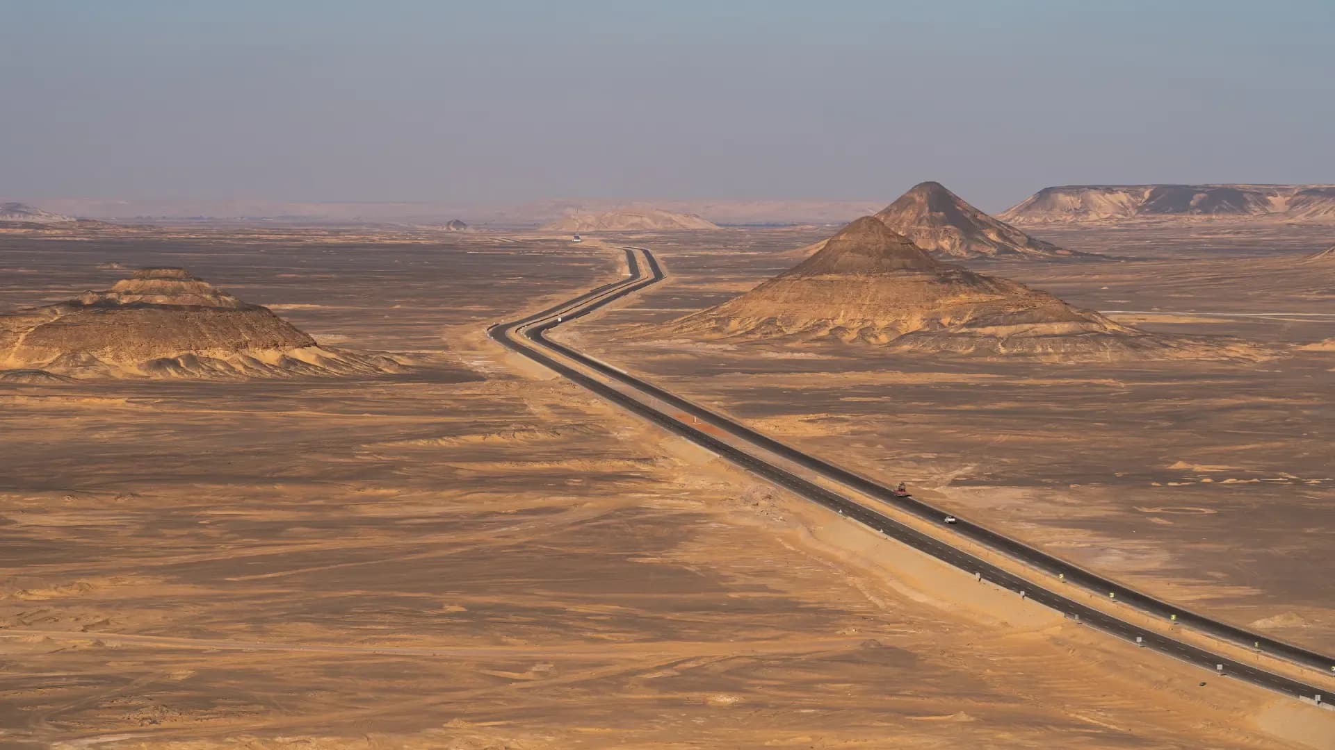 A highway winding through Egypt's Black Desert, with a truck carrying goods