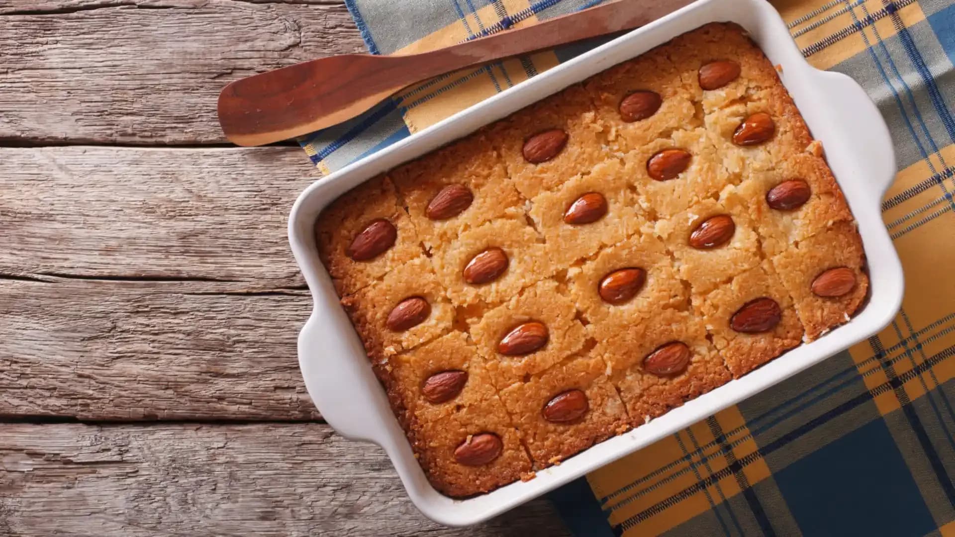 A tray of basbousa cut into equal pieces, each topped with an almond