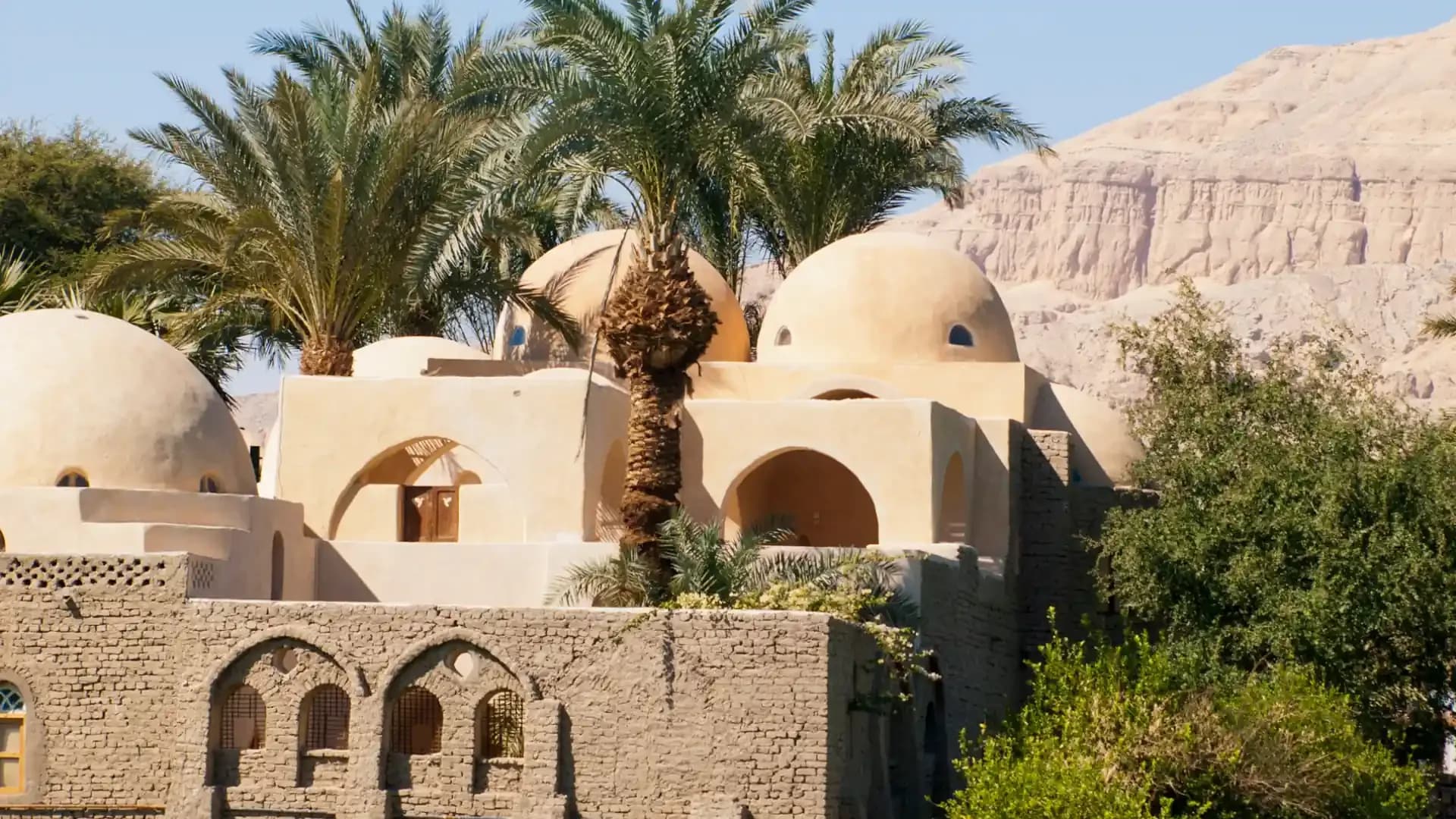 A domed house among palm trees on the west bank of Luxor, with the Theban hills behind
