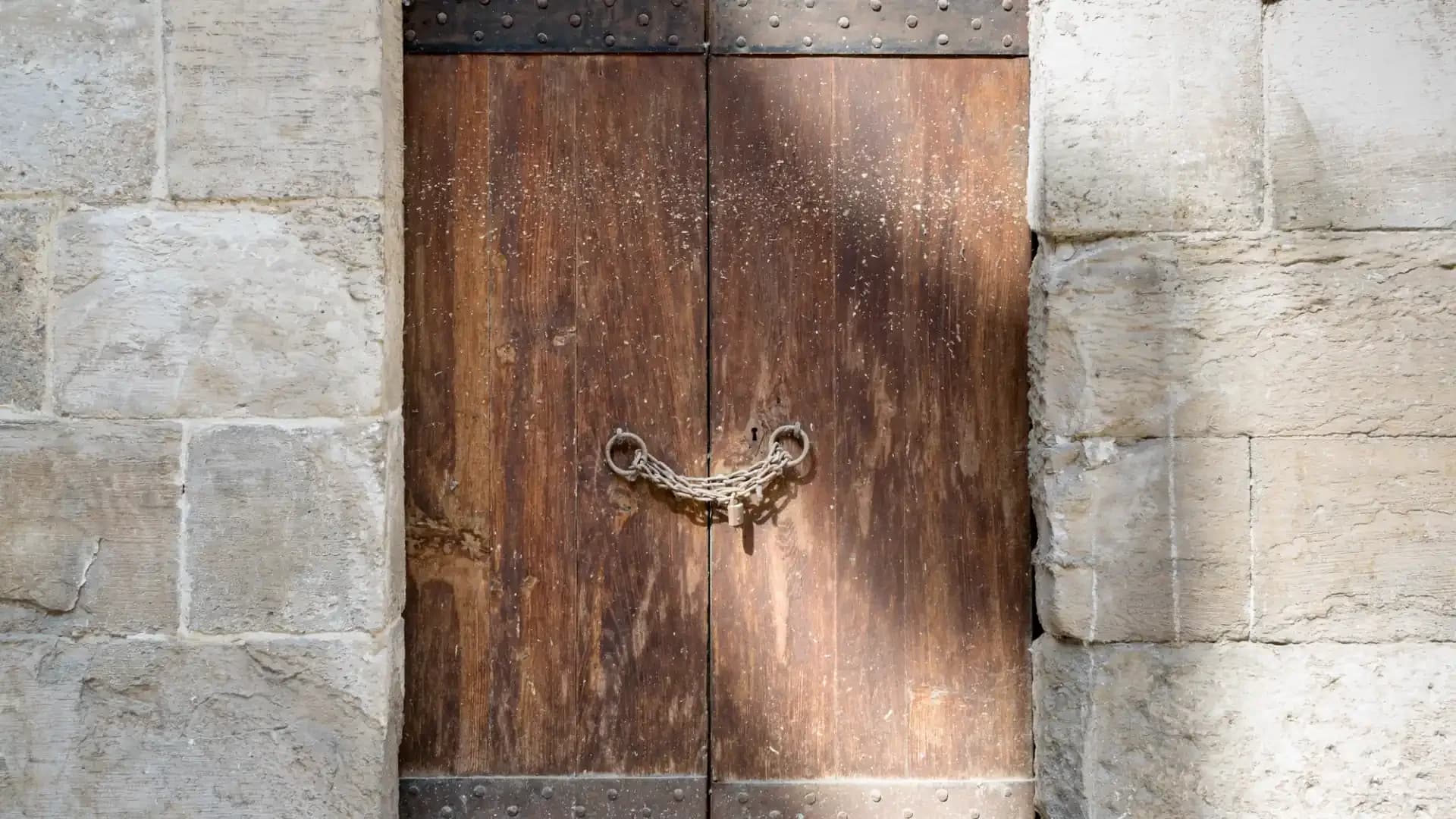 An old wooden double door with iron straps, chained and padlocked, in a limestone wall in Cairo