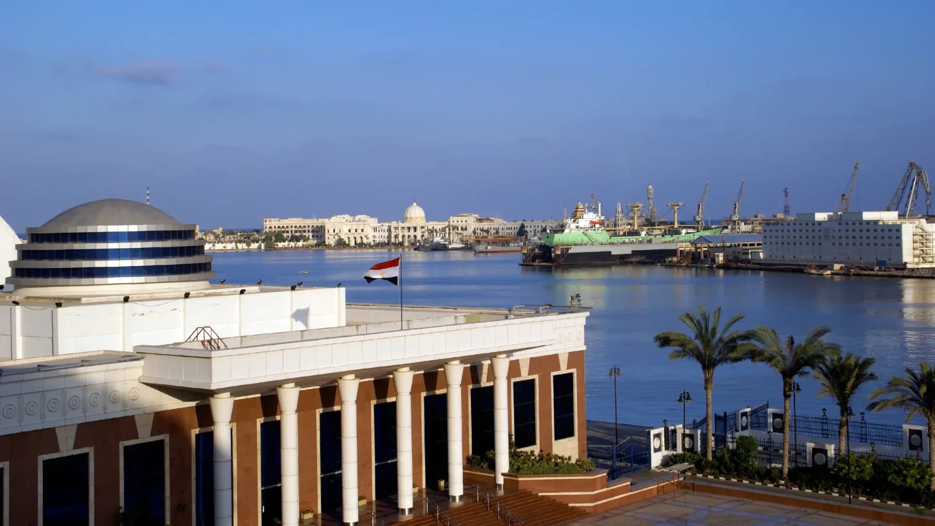 The port of Alexandria with ships and cranes, Ras El Tin Palace across the harbour