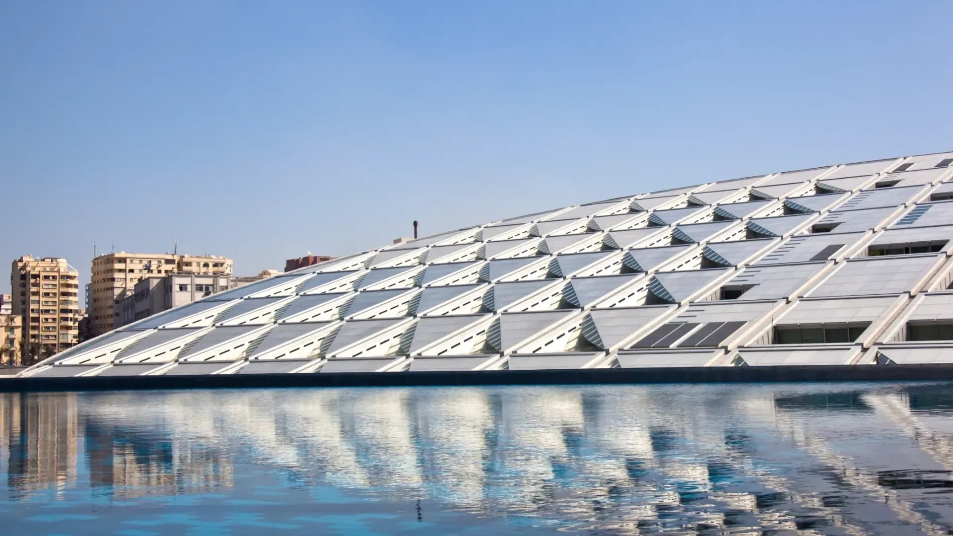 The roof of the Bibliotheca Alexandrina reflected in its pool