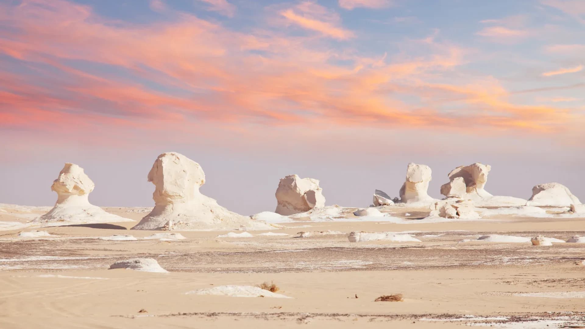 Chalk rock formations in Egypt's White Desert under a pink sunset sky